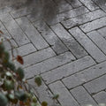 Hazlebury limestone tumbled and etched klinkers gray rectangular pavers arranged in a wet herringbone pattern
