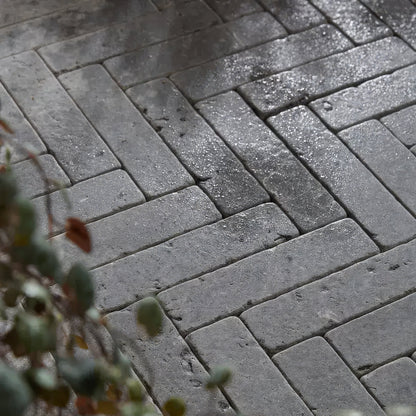 Hazlebury limestone tumbled and etched klinkers gray rectangular pavers arranged in a wet herringbone pattern