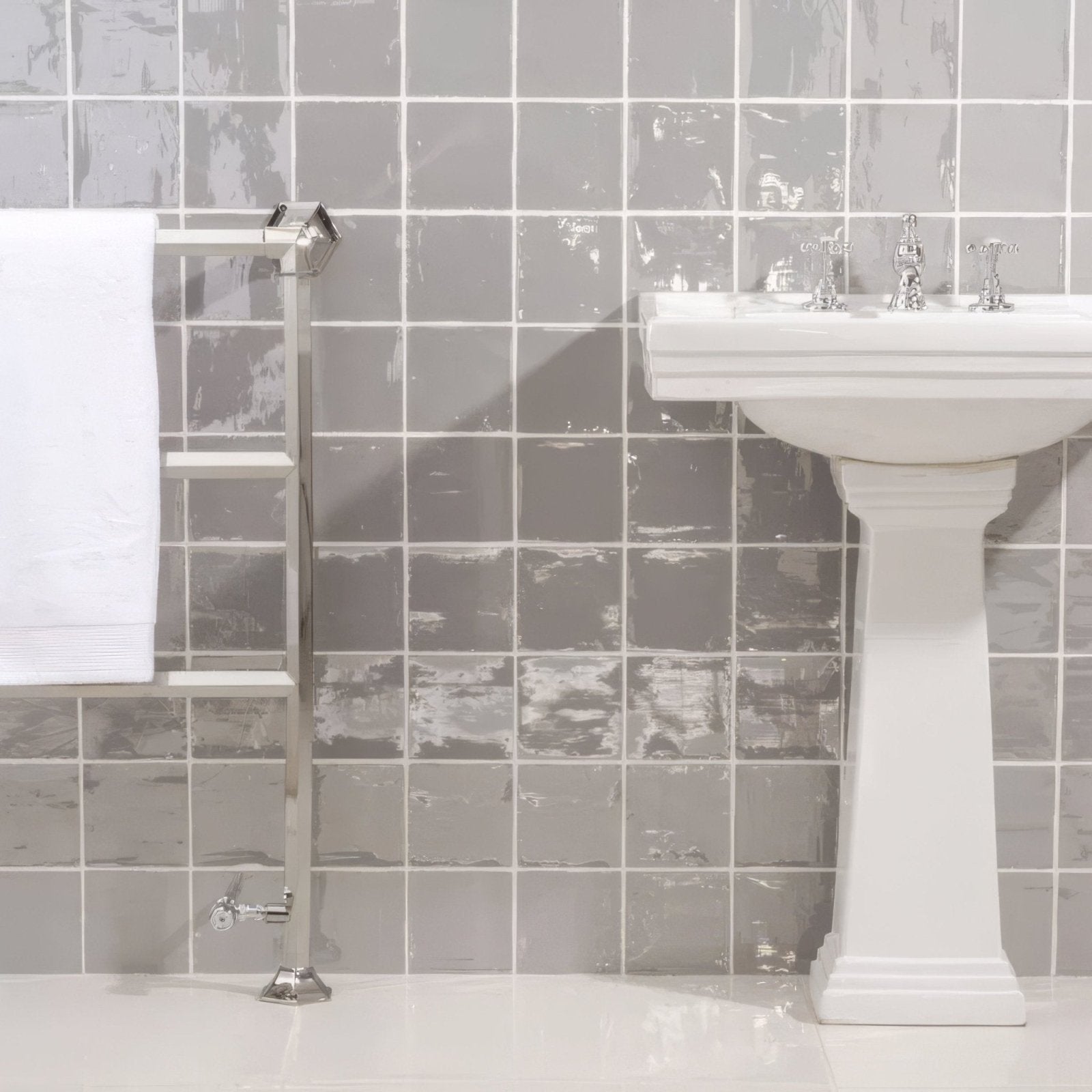 White pedestal sink with chrome faucets featuring heather field tile backsplash in a bathroom setting