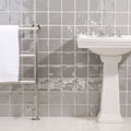 White pedestal sink with chrome faucets featuring heather field tile backsplash in a bathroom setting