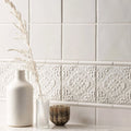 A tall matte white ceramic vase with a slender neck and rounded body in the helmingham field tile design