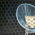 Hera Metallic Hexagon Mosaics black hexagon glass mosaic with a light blue wicker chair