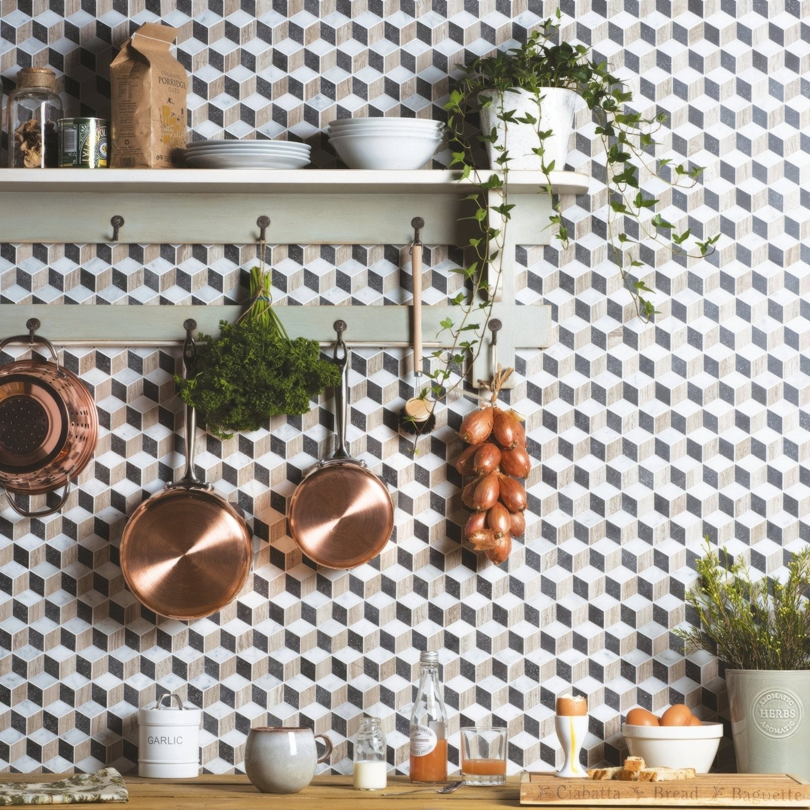 Three copper pans hang on a white rack against a herald marble mosaic geometric-patterned wall