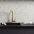 Hexagon Matt Carrara White white marble hexagon mosaic behind a gold kitchen tap
