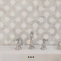 High Society Marble Guggenheim white marble mosaic with a chrome three-handle tap and crystal knobs