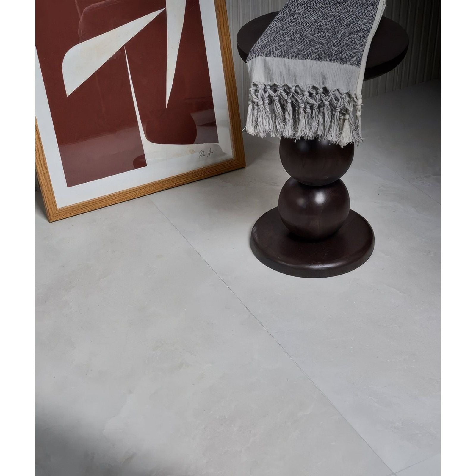 A gray and white woven throw blanket with textured pattern and fringed edges on a dark wooden table