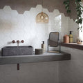 Gray marble rectangular sink with copper faucets installed against hope white hexagon gloss ceramic wall tiles