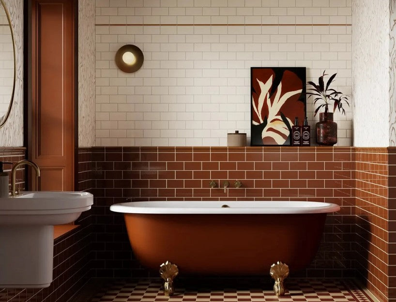 Cream and burgundy metro wall tiles around a roll-top bath with brass feet