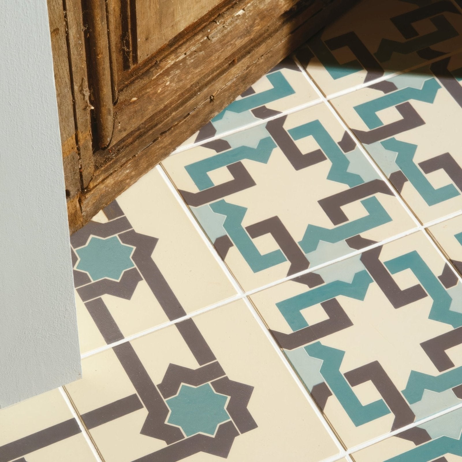 Beige tiles with teal and dark brown geometric patterns from the iberian border dark grey and dark jade collection on white