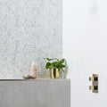Gold metallic planter holding green leafy plant on ice white rectified ceramic tile 60x30