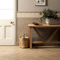 A beige woven jute basket with two sturdy handles next to a wooden table from ickworth chelsea collection