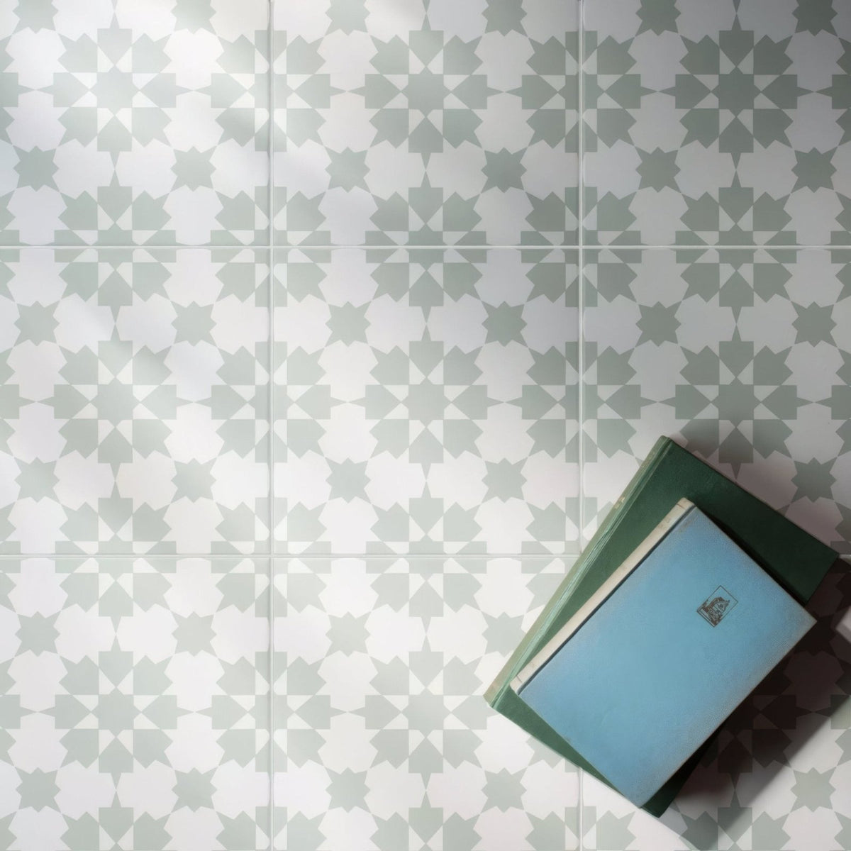Stack of books with light blue and dark green covers featuring simple rectangular labels for infusion ornelas patterned tile design