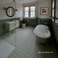 White clawfoot bathtub with black fixtures set on infusion ornelas patterned tile floor in a bathroom setting