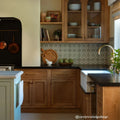 Wooden kitchen cabinets with glass doors and brass hardware featuring infusion ornelas patterned tile backsplash