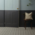 Striped beige and gray pillow with frayed edges on dark wood chair featuring infusion st etienne patterned tile design