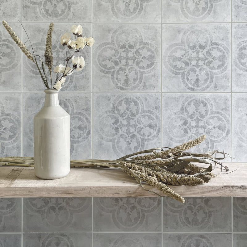 Cream-colored ceramic vase with slender neck holding dried white flowers and grasses beside istria barban patterned tile