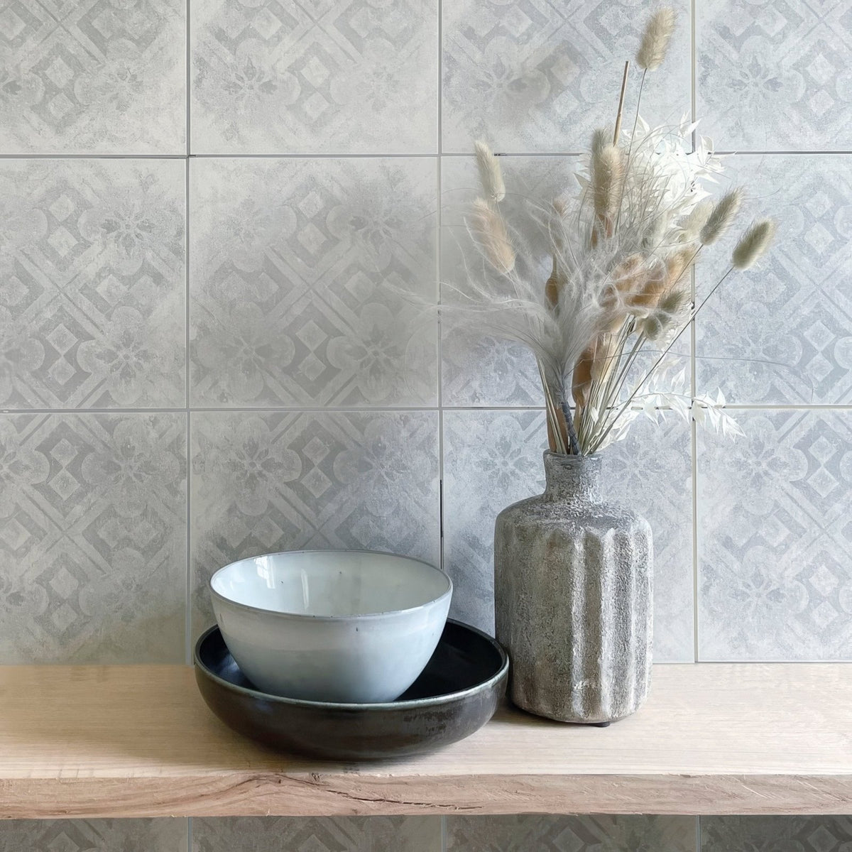 A matte gray ceramic vase with vertical ridges holding dried pampas grass beside an istria pula patterned tile