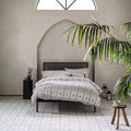 Black metal bed frame with vertical slats and matching legs displayed on istria ravni patterned tile floor