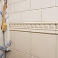 Cream-colored ceramic ivory field tile border with repeating geometric pattern for wall or floor decoration