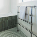 Chrome-finished radiator towel rack with white textured towel draped over top bar in ixworth forest bar tile