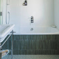 White ceramic bathtub with chrome fixtures and dark green ixworth forest bar ceramic tiles on lower wall