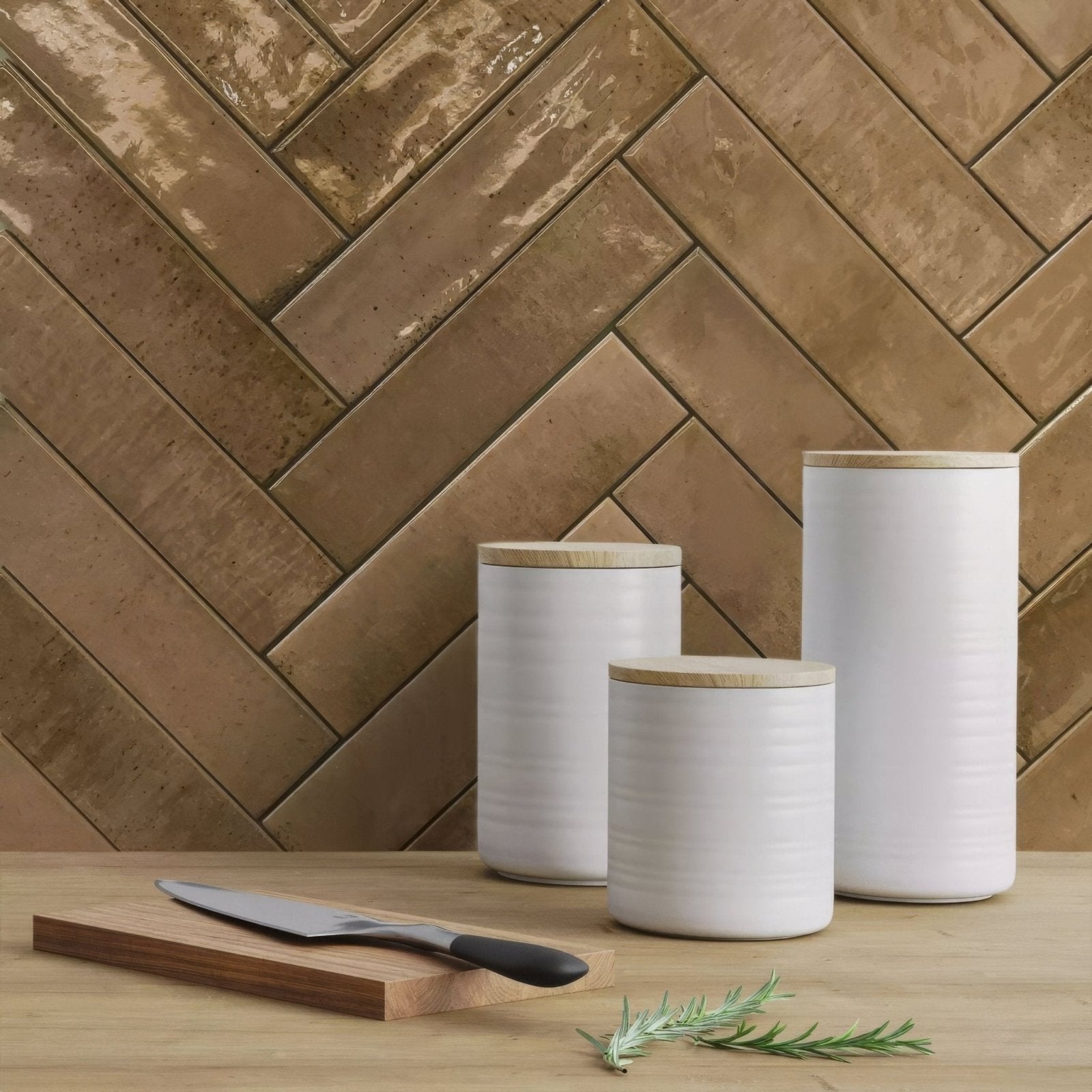 Three white ceramic canisters with light wood lids arranged in descending size for kitchen storage use