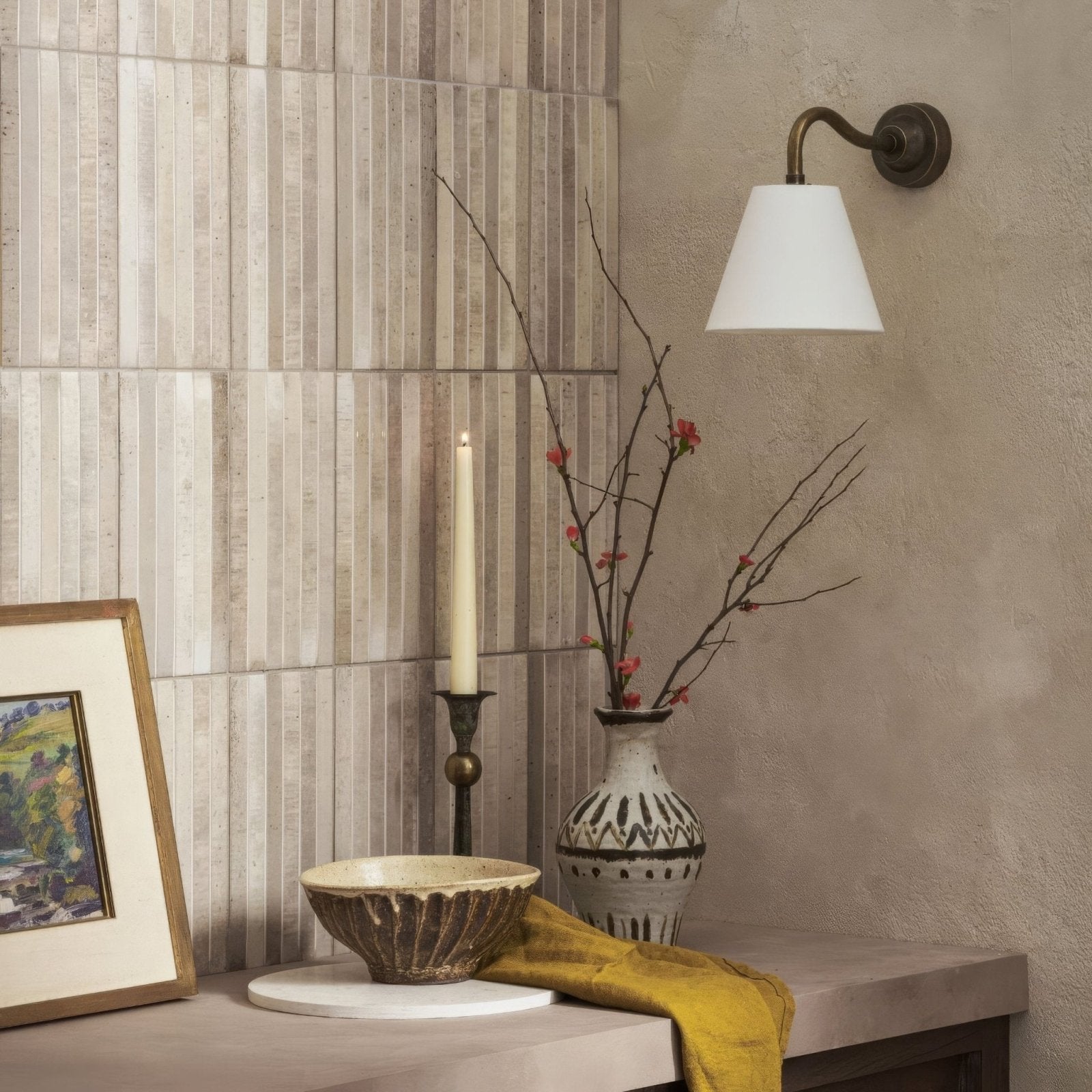 A white ceramic ixworth ivory bar tile with black geometric patterns holding delicate branches with small red blossoms
