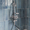 Chrome-finished Ixworth Sky Brick Tile shower mixer with white ceramic knobs and flexible hose against blue tiles