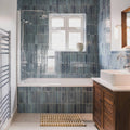 The bathroom features sleek dark blue ixworth sky brick tiles with a glossy finish around the bathtub and shower area