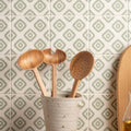 Jacquard sage three wooden spoons with natural wood grain in a speckled beige ceramic utensil holder