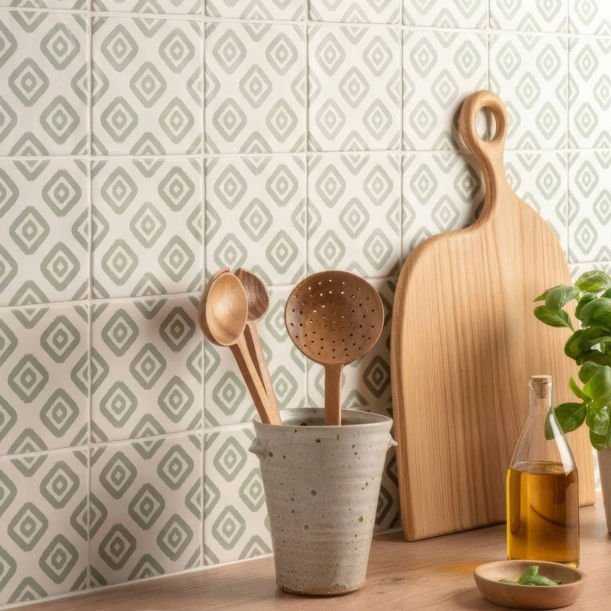 A rustic ceramic jacquard sage utensil holder with a speckled gray finish holding wooden spoons and ladles
