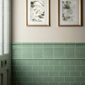 Jade breeze half tile featuring a decorative mint green ceramic border with embossed floral pattern above subway tiles