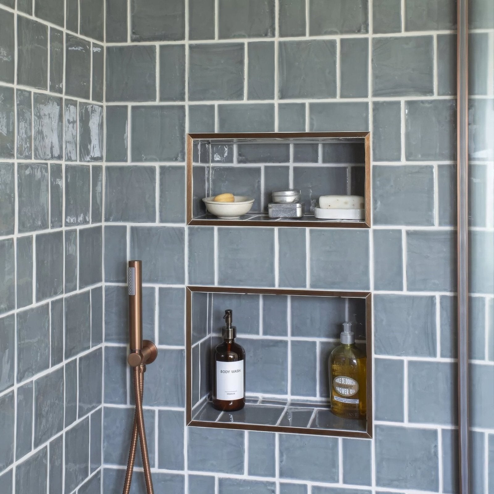 Two rectangular recessed shelves with bronze frames set in a gray tiled wall featuring jaipur dartmouth green rectangle glazed tiles
