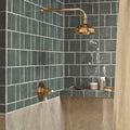 Brass showerhead with curved arm and classic design mounted on dark green jaipur dartmouth green glazed tile walls