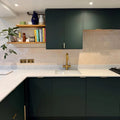 Gold-toned kitchen faucet with modern minimalist design paired with jaipur old ochre rectangle glazed tile background