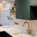 Gold-toned kitchen faucet with curved spout and cross-handle design shown with jaipur old ochre rectangle glazed tile