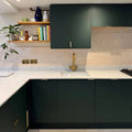 Jaipur old ochre square glazed tile in a kitchen with dark green matte cabinets and gold-toned handles and faucet