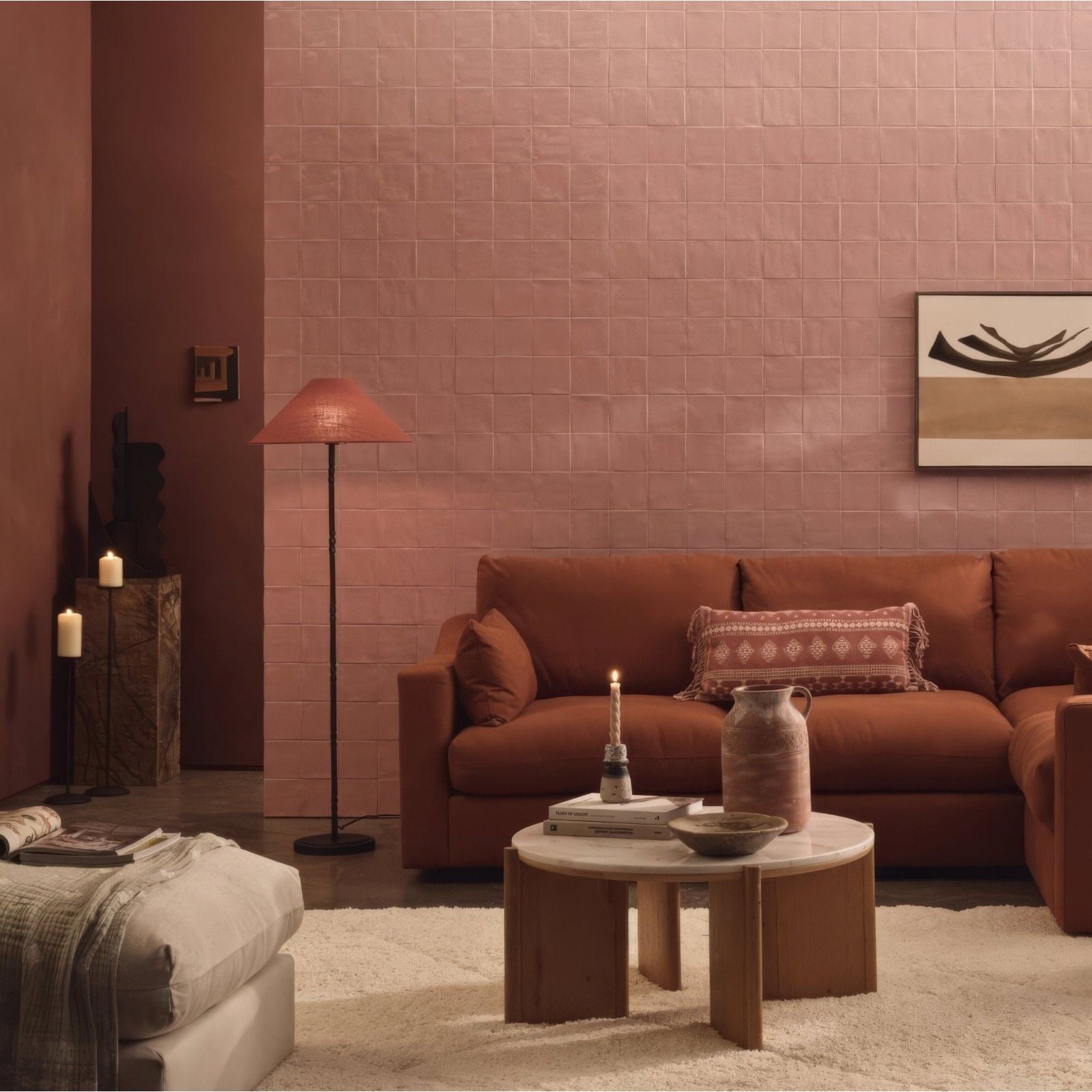 Rust-colored leather sofa with patterned throw pillow against pink glazed jaipur pompeiian red square tile walls