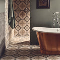 Copper freestanding bathtub with polished reflective surface and elegant curved design featured in jaipur sikkar patterned tile setting