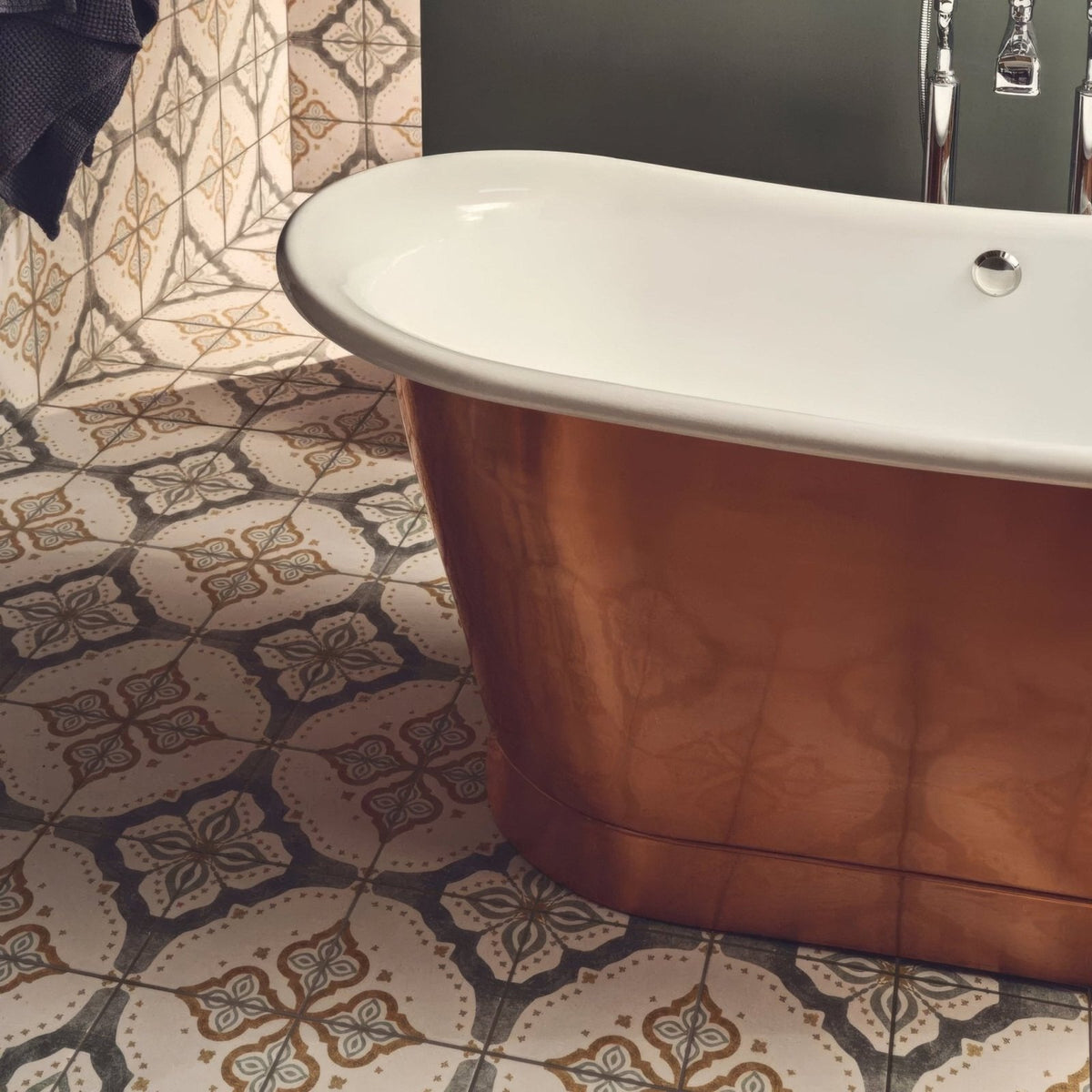 Copper-finished freestanding bathtub with white porcelain interior and chrome fixtures displayed with jaipur sikkar patterned tile