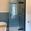 Modern glass shower enclosure with black frame and handle featuring dark blue Jaipur Storm Square glazed tiles