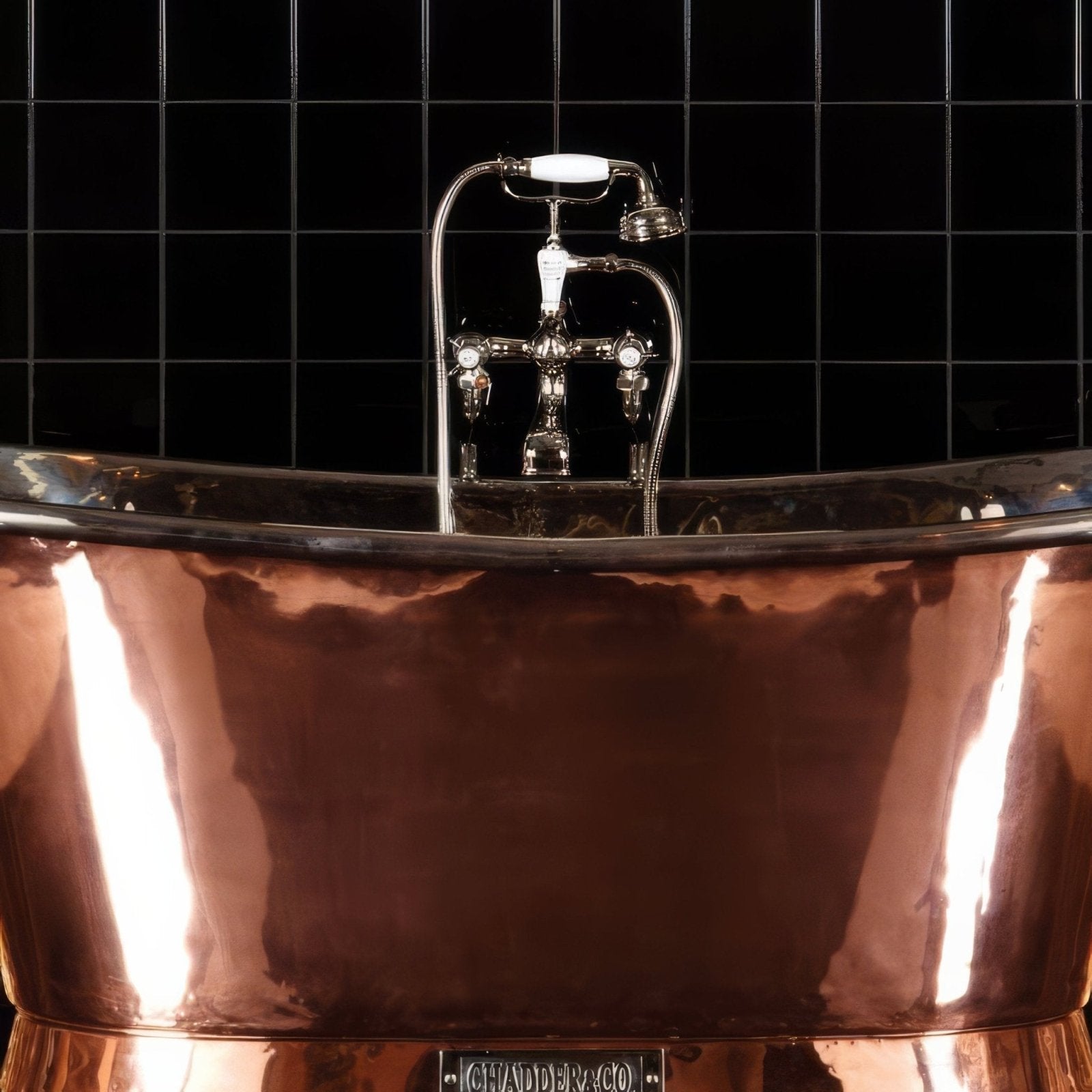 Shiny copper bathtub with polished reflective surface and chrome faucet displayed with jet black field tile background