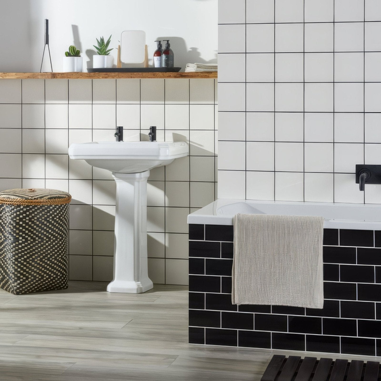 White ceramic pedestal sink with black faucet fixtures featured in jet black half tile bathroom design
