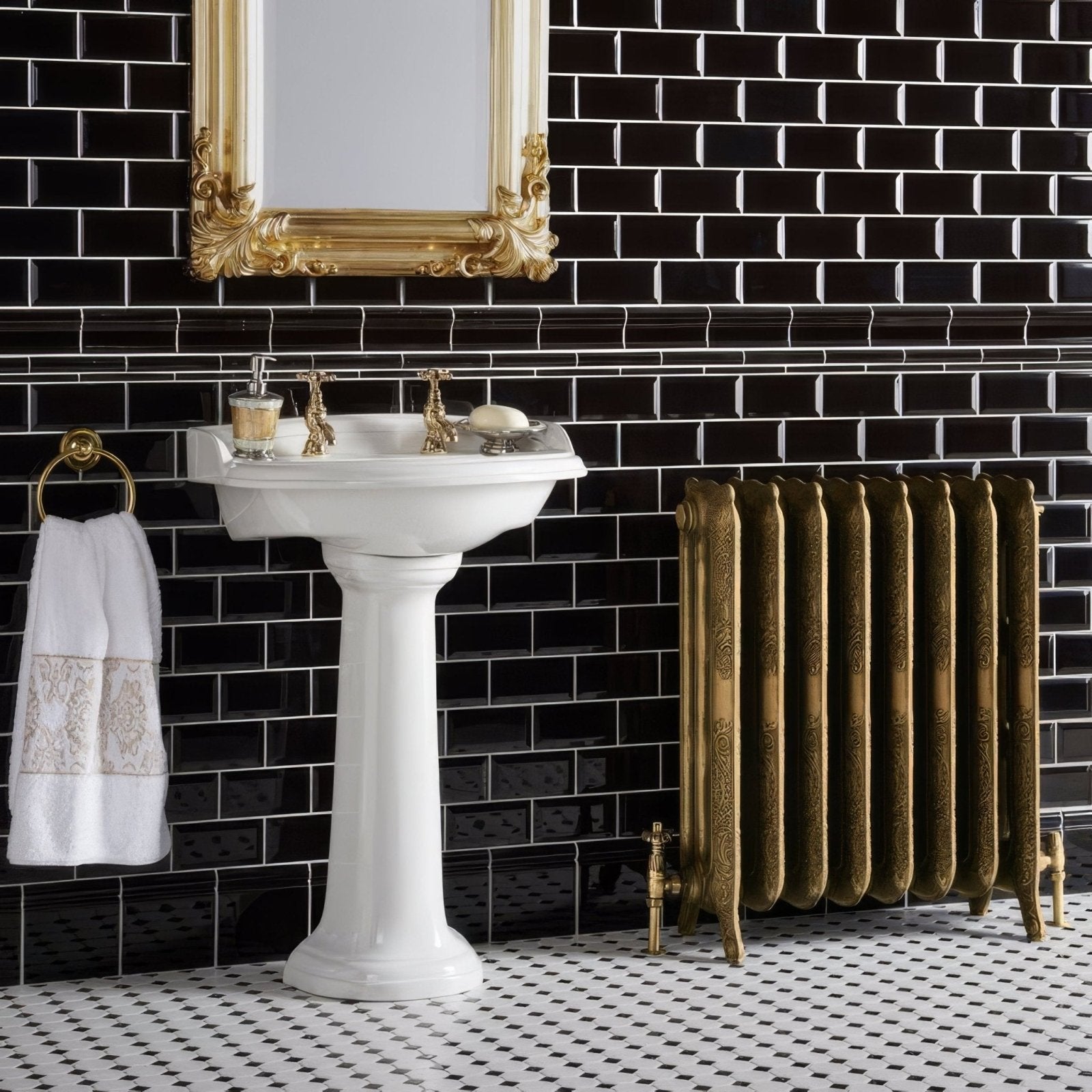 White ceramic pedestal sink with gold-toned faucets and ornate mirror above jet black skirting tile wall