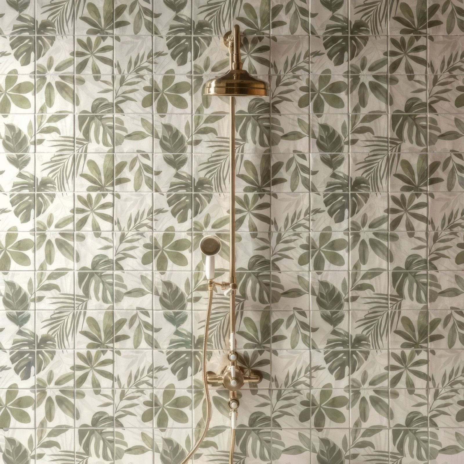 Brass showerhead with matching faucet and handheld sprayer against jungle grove 16 tile panel featuring green leaf patterns