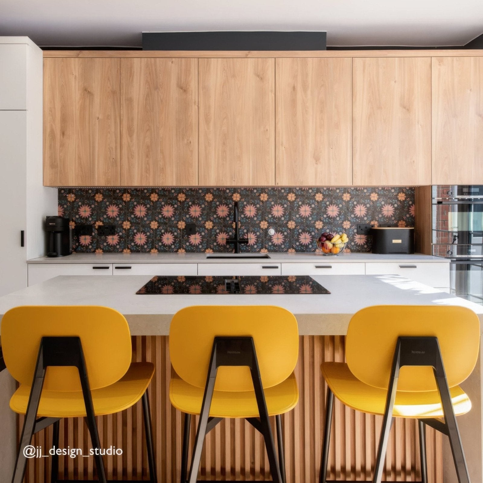 Three vibrant yellow bar stools with sleek black metal frames complement kelmscott blackwell patterned tile flooring
