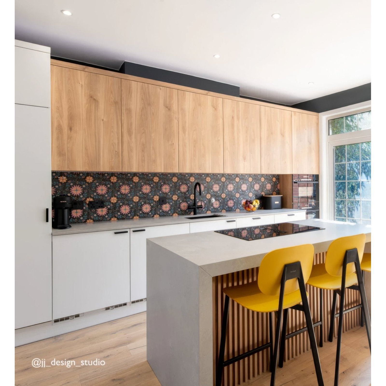 Modern kitchen featuring kelmscott blackwell patterned tile with light wood cabinets white countertops and yellow stool