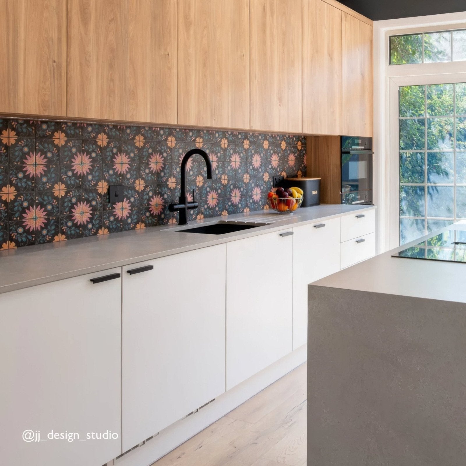 Modern kitchen featuring kelmscott blackwell patterned tile dark floral backsplash with light wood and white cabinets