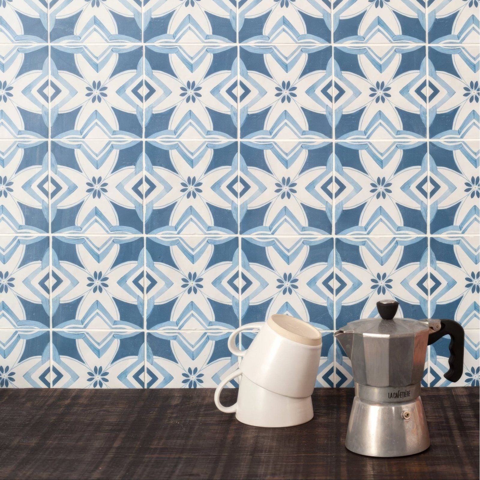 Silver la cimbali moka pot with black handle and lid featured on a kelmscott brantwood blue patterned tile background