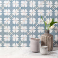 Rustic textured ceramic vase with matte grayish brown finish holding white flowers on Kelmscott Coleton blue patterned tile
